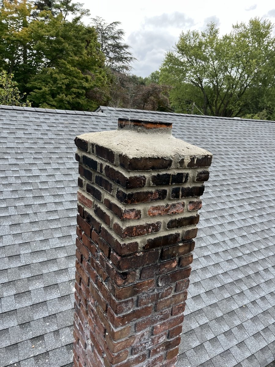 Chimney with newly poured crown and cap on residential roof