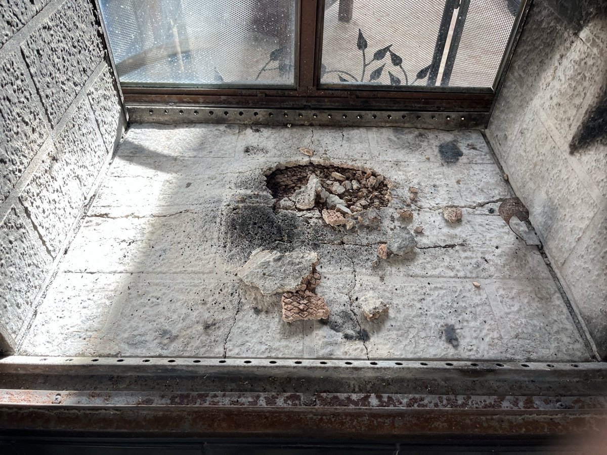 Damaged firebox floor with holes and crumbling mortar requiring repair
